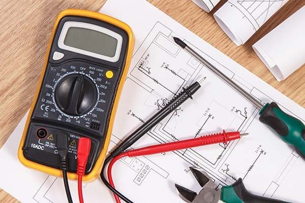 Multimeter, snips, and screw driver sitting on electrical plans